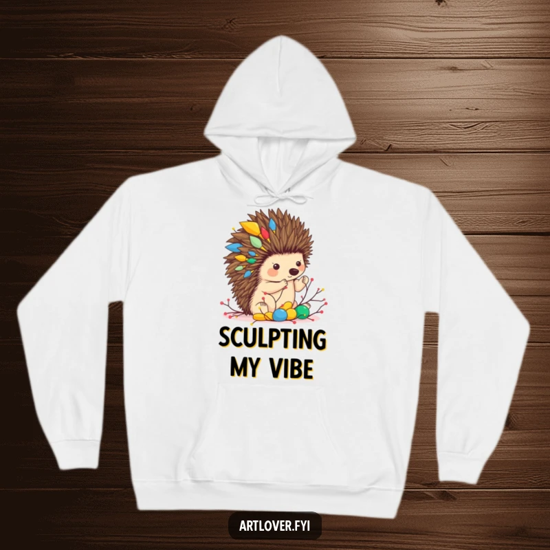 Funny hoodie depicting a hedgehog artist focused on building a colorful abstract sculpture out of twigs, radiating warmth and creativity.
